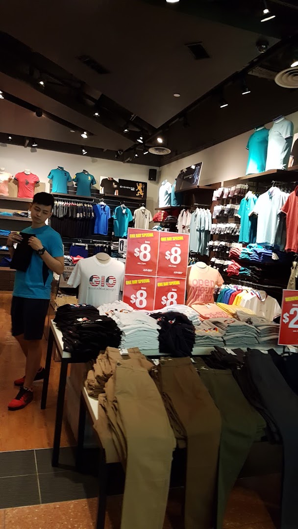 A customer browses clothing items, including shirts and pants, inside a Giordano retail store.