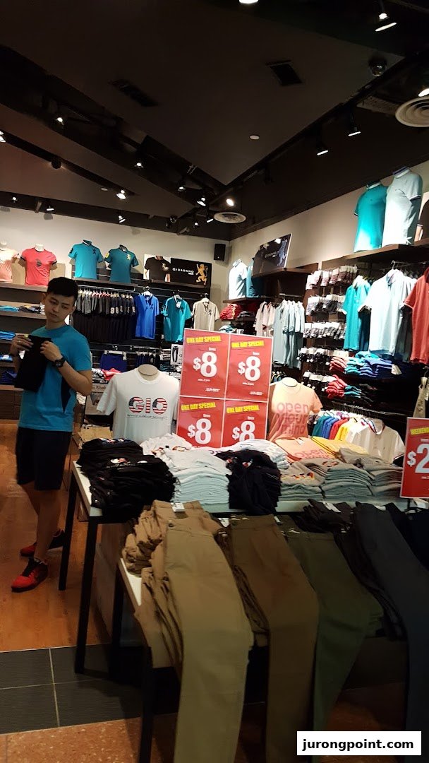 A customer browses clothing items, including shirts and pants, inside a Giordano retail store.
