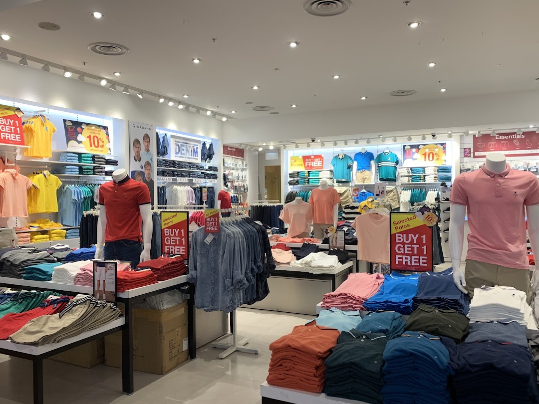 An interior view of a Giordano apparel store showcasing casual wear, polos, and denim with prominent 'Buy 1 Get 1 Free' offers.