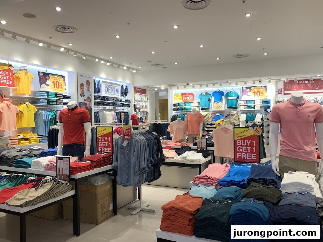 An interior view of a Giordano apparel store showcasing casual wear, polos, and denim with prominent 'Buy 1 Get 1 Free' offers.
