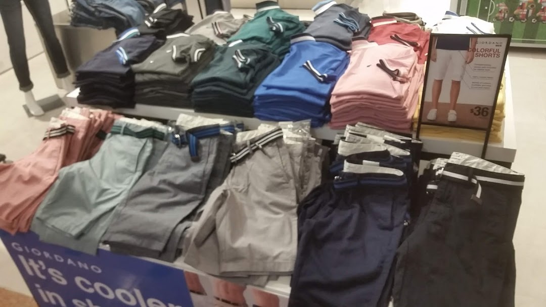 A vibrant display of colorful polo shirts and shorts on racks inside a Giordano retail store.