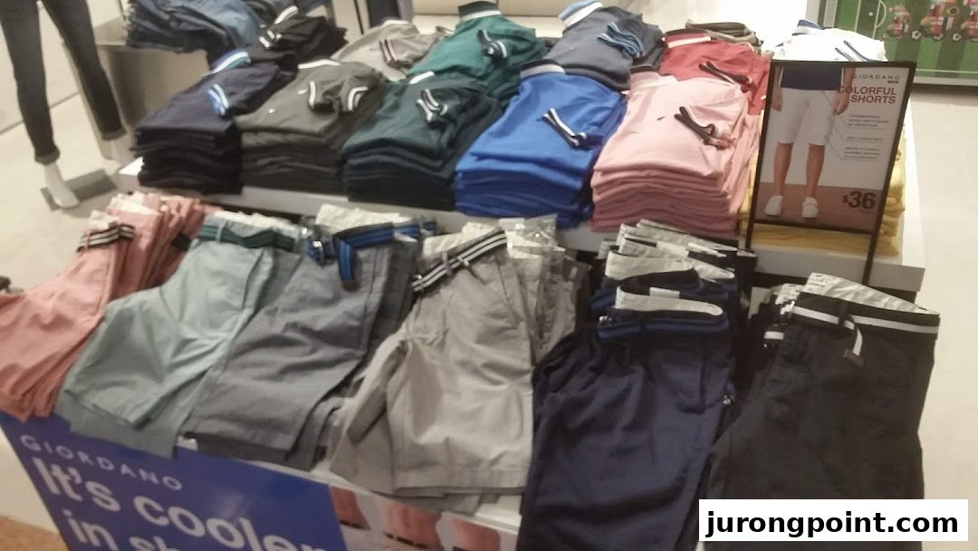 A vibrant display of colorful polo shirts and shorts on racks inside a Giordano retail store.