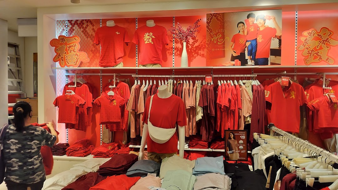 Interior view of a Giordano store featuring a vibrant red clothing collection and festive Chinese New Year decorations.