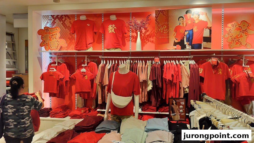 Interior view of a Giordano store featuring a vibrant red clothing collection and festive Chinese New Year decorations.