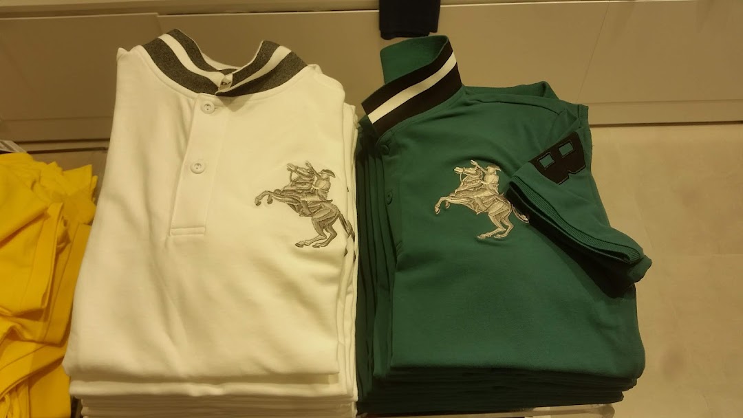 Two folded polo shirts, white and green, with a horse rider emblem, displayed in a retail store.