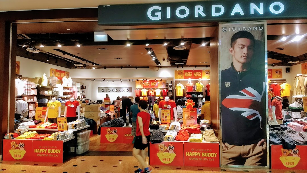 The vibrant entrance of a Giordano clothing store, showcasing diverse apparel and promotional displays.