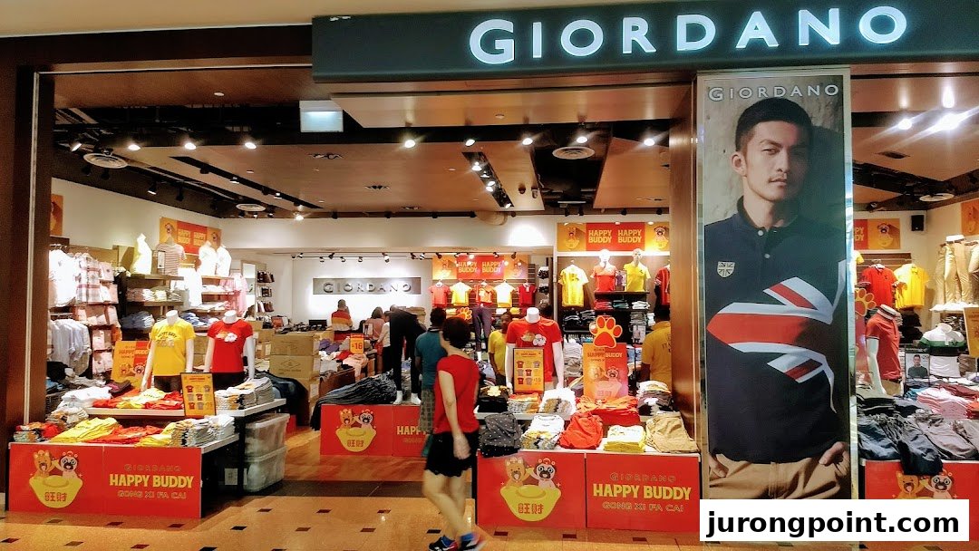 The vibrant entrance of a Giordano clothing store, showcasing diverse apparel and promotional displays.
