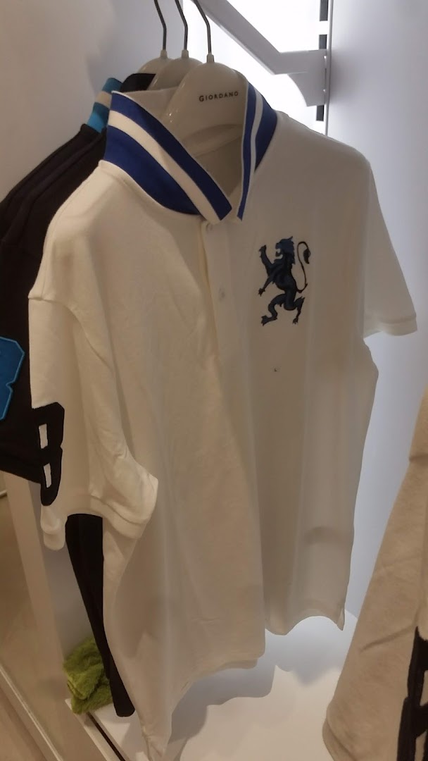 A white polo shirt with a blue-striped collar and a black lion emblem hangs in a Giordano store.