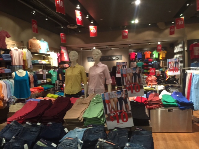 Interior view of a Giordano store showcasing colorful casual wear, denim, and sale items with mannequins.