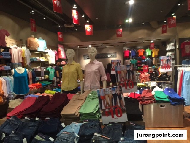 Interior view of a Giordano store showcasing colorful casual wear, denim, and sale items with mannequins.