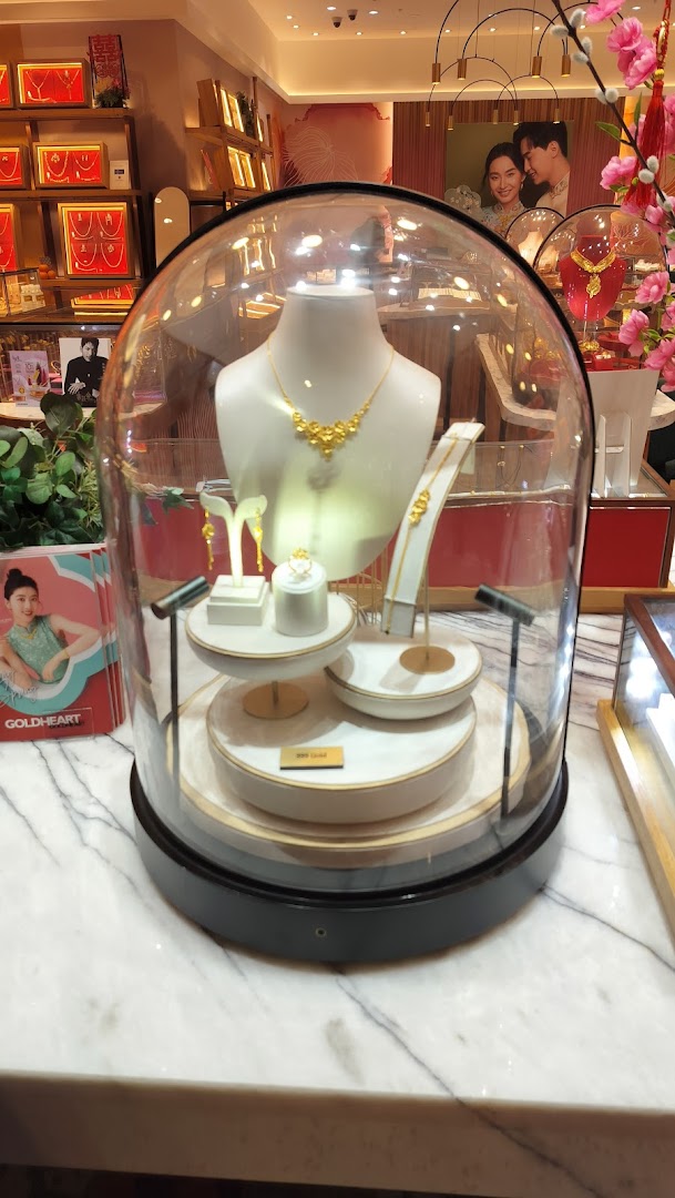 A display of exquisite gold jewelry, including a necklace, earrings, and ring, showcased under a glass dome.