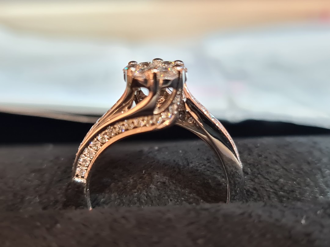 A close-up of a sparkling diamond ring with intricate band details, displayed on a dark surface.