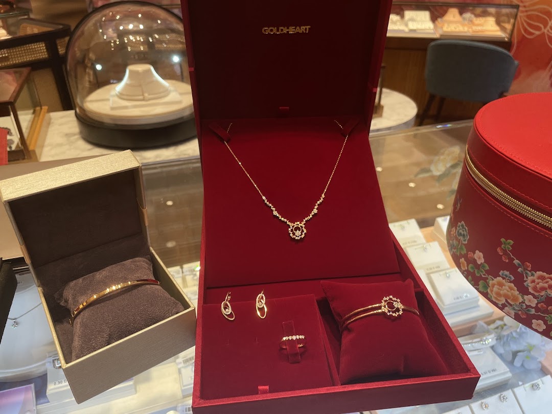 A close-up of exquisite gold and diamond jewelry sets displayed in red velvet boxes at Goldheart Jewelry.