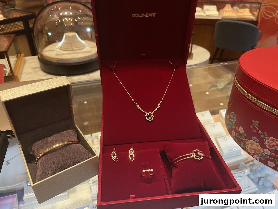 A close-up of exquisite gold and diamond jewelry sets displayed in red velvet boxes at Goldheart Jewelry.
