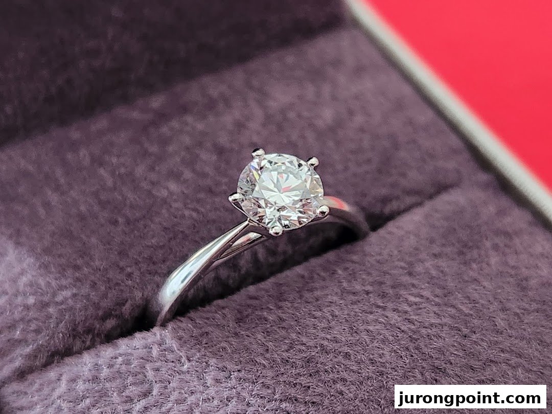 A close-up of a sparkling diamond solitaire ring set in a silver band, resting in a purple velvet box.