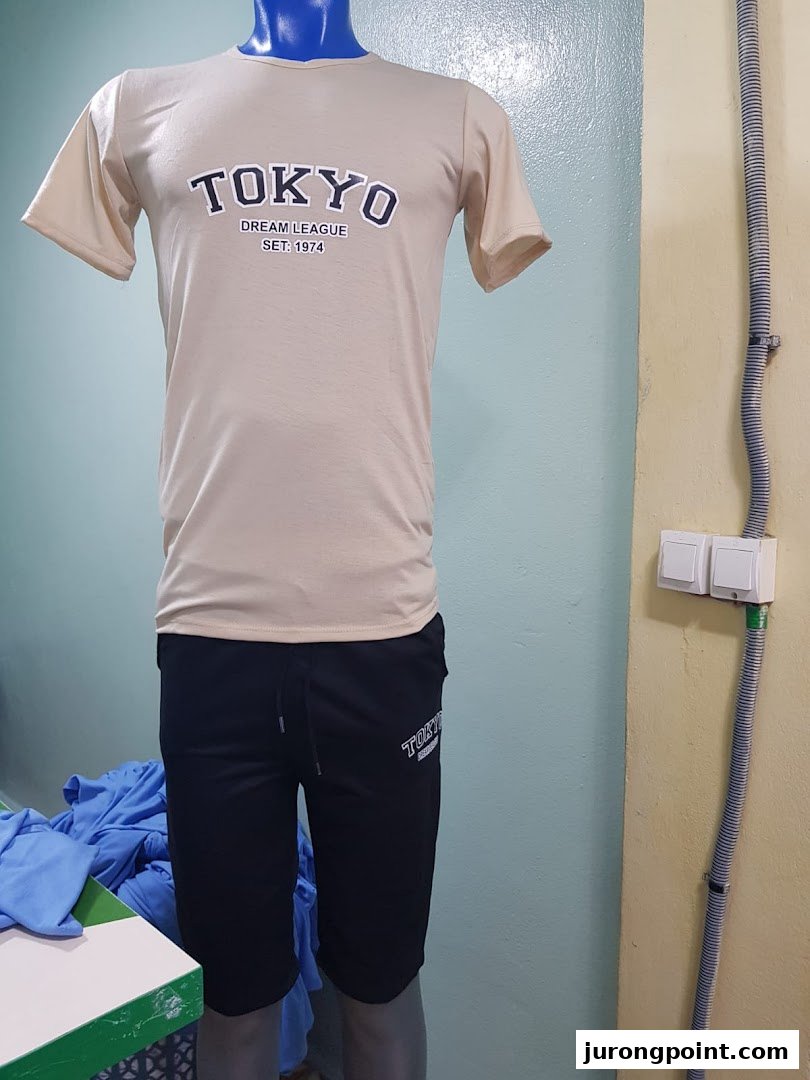 Mannequin displays a beige t-shirt with 'TOKYO' print and black shorts inside a retail shop.