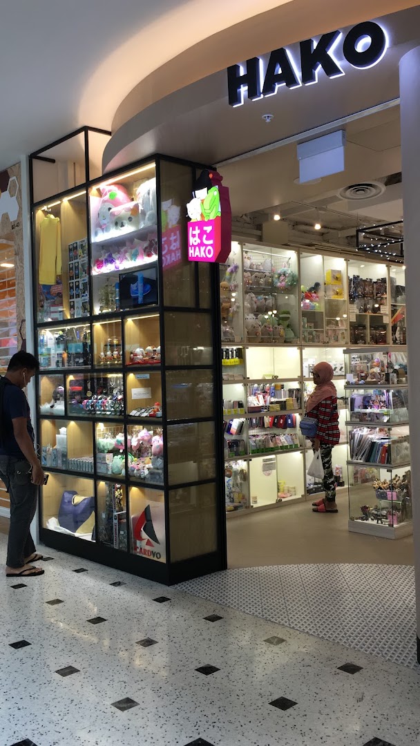Hako shop entrance showcasing diverse gifts and novelty items in illuminated display cases, with customers browsing.