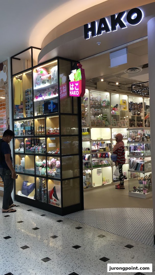 Hako shop entrance showcasing diverse gifts and novelty items in illuminated display cases, with customers browsing.