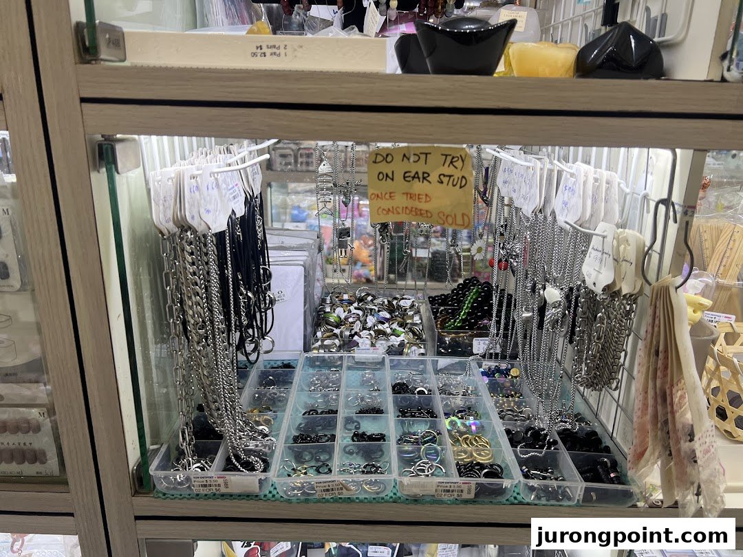 A retail display case showcasing various fashion accessories, including necklaces, rings, and ear studs.