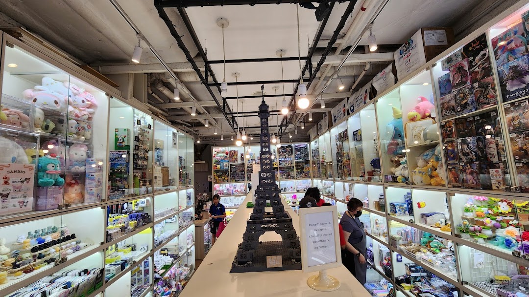 Interior view of Hako, a shop filled with display cases showcasing toys, collectibles, and plushies, with a large Eiffel Tower model.