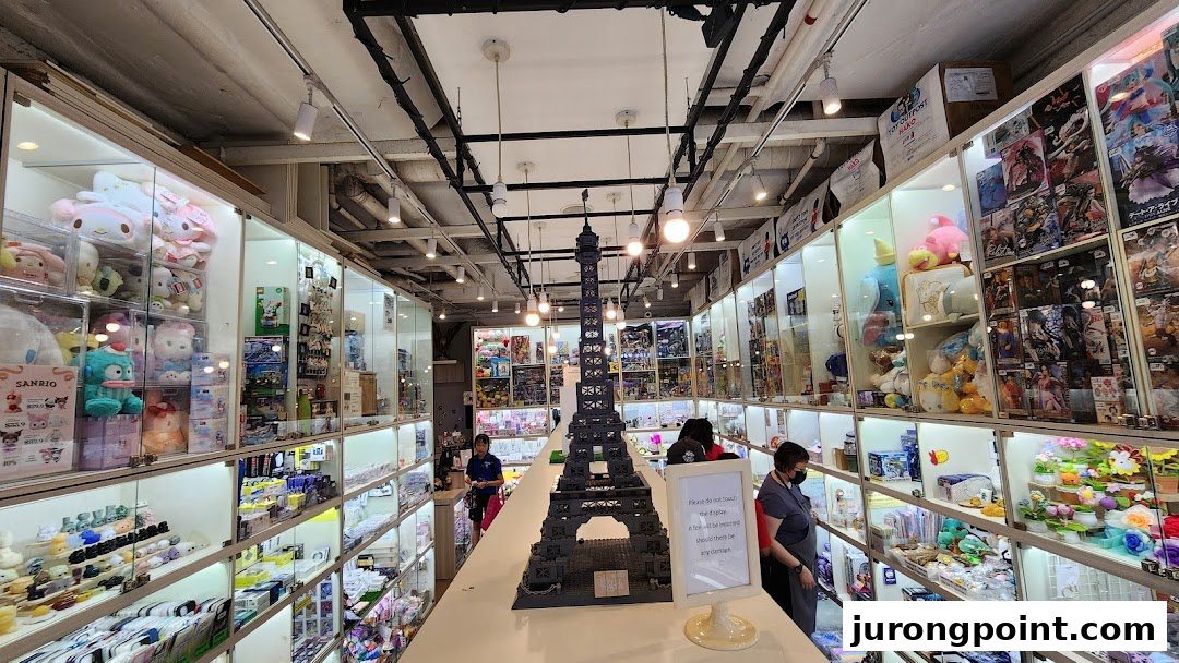 Interior view of Hako, a shop filled with display cases showcasing toys, collectibles, and plushies, with a large Eiffel Tower model.