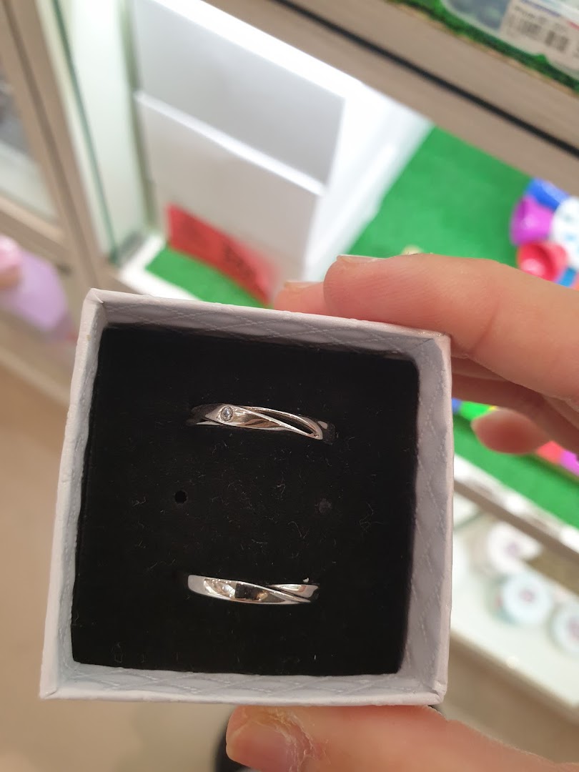 A hand holds a small box displaying a pair of elegant silver rings with subtle designs.