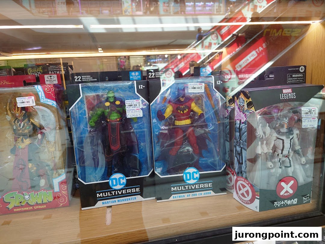 A display case showcasing various collectible action figures from popular franchises like DC, Marvel, and Spawn.