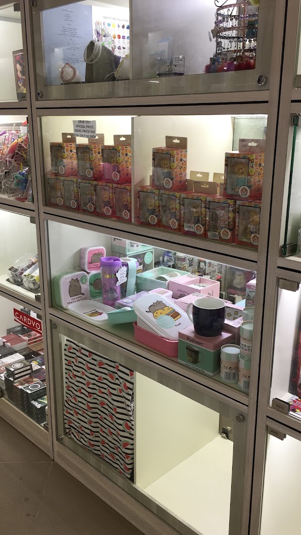 Illuminated glass display cases showcasing diverse merchandise, including collectibles, accessories, and Pusheen-themed items.