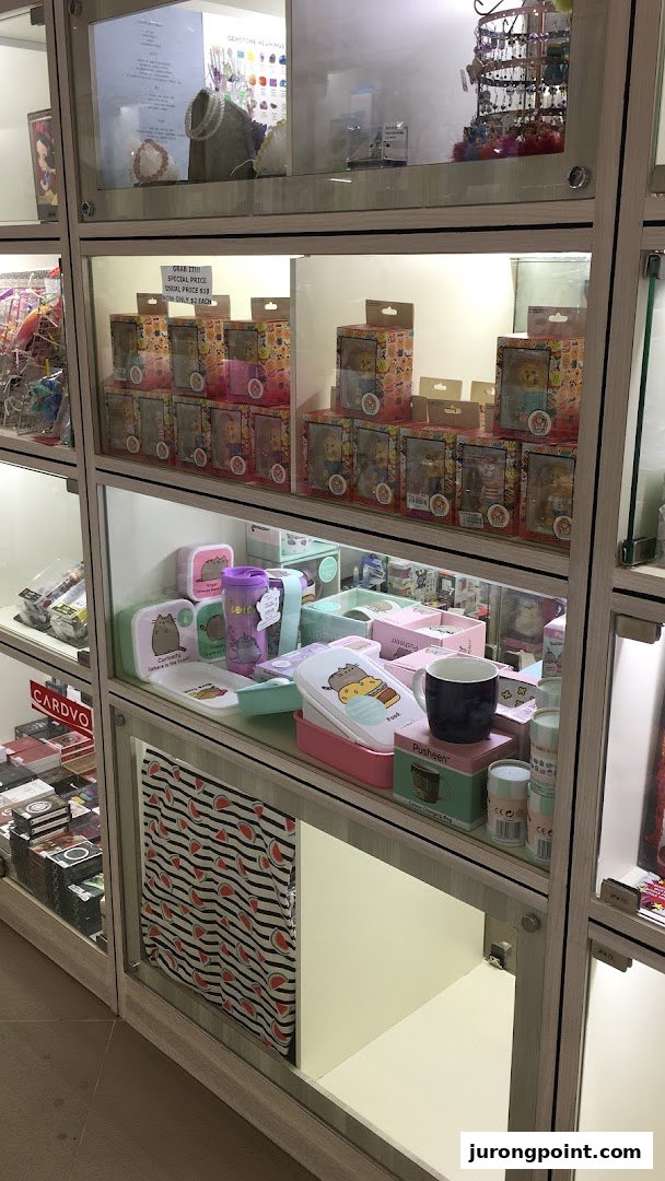 Illuminated glass display cases showcasing diverse merchandise, including collectibles, accessories, and Pusheen-themed items.