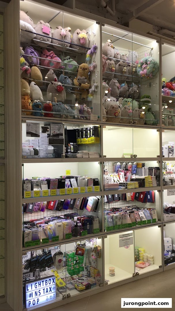 Multiple glass display cases filled with plush toys, phone accessories, and novelty items inside a retail store.