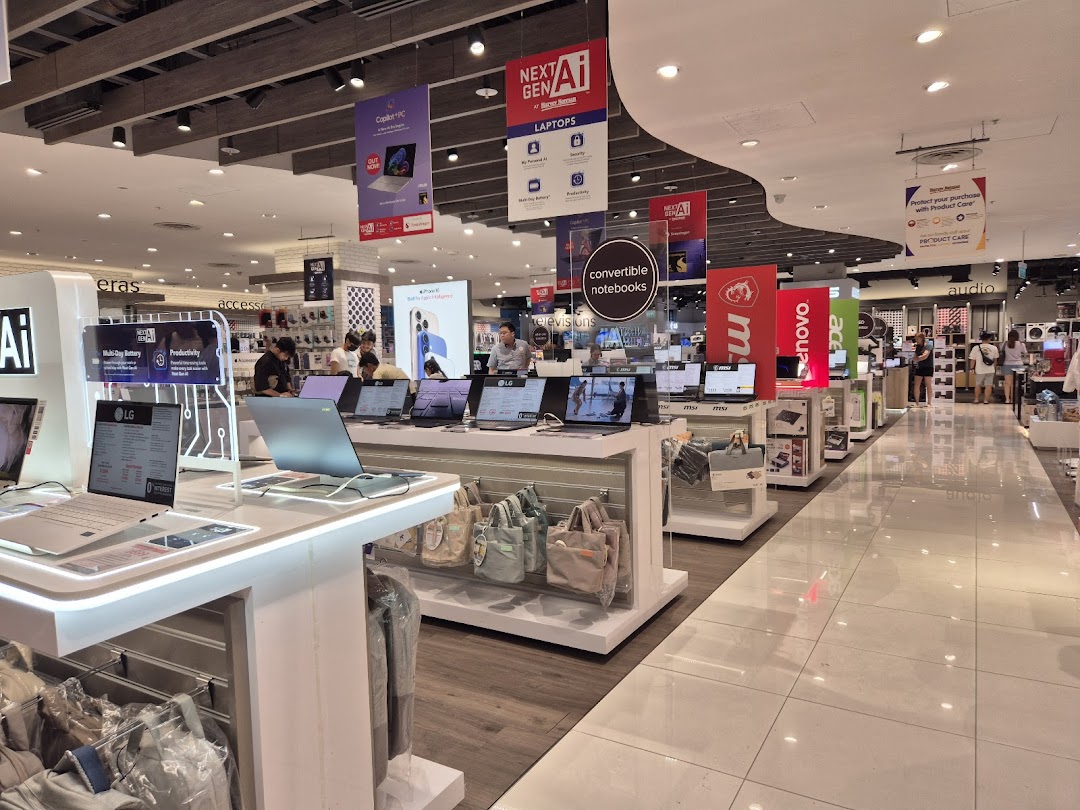 A wide interior view of Harvey Norman's electronics section, showcasing various laptops and tech displays.