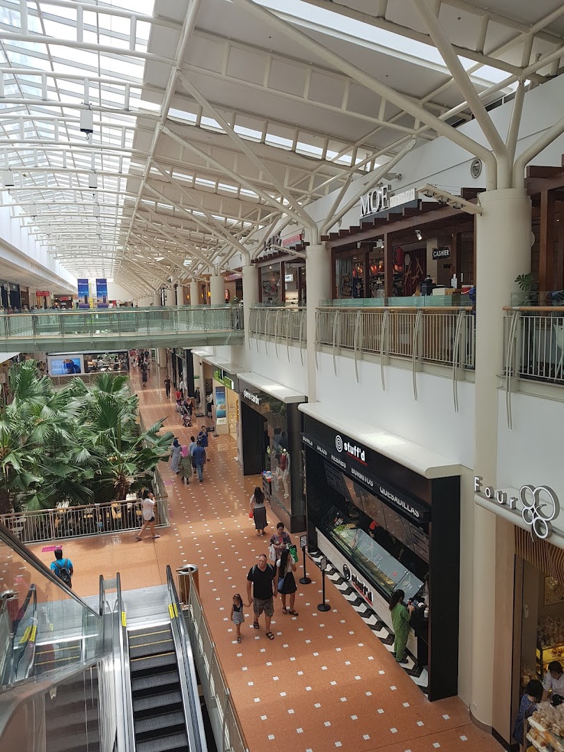 A vibrant interior view of a multi-level shopping mall with various shops and shoppers.