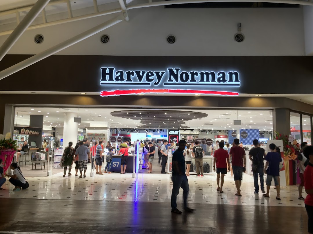 The brightly lit entrance of Harvey Norman at Jurong Point, bustling with shoppers exploring electronics and home goods.
