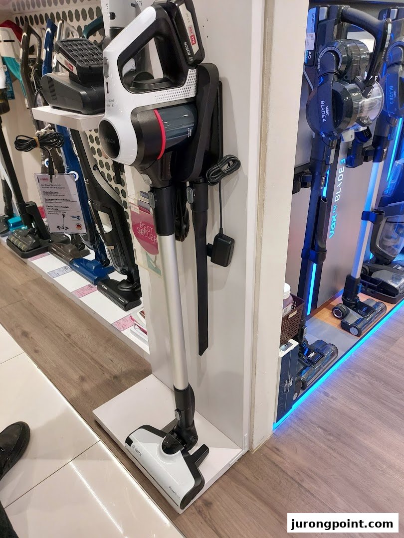 A display of modern cordless vacuum cleaners, including Bosch and Vax models, inside a retail store.