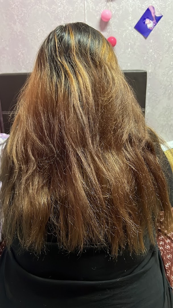 Back view of a person with long, light brown hair, showing roots and highlights.