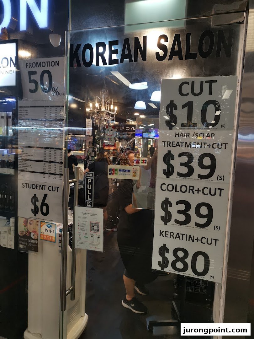 The shop front of HI Salon, a Korean salon, displaying various hair services and prices on its glass entrance.