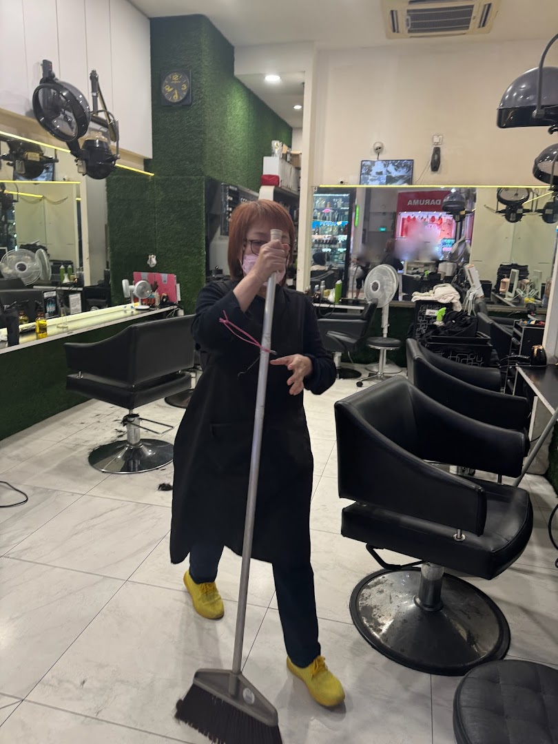 An employee sweeps the floor inside HI Salon, showcasing the clean and well-maintained interior.