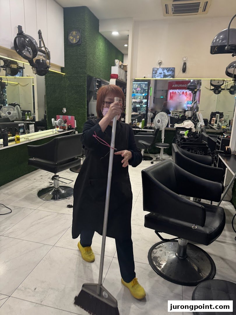 An employee sweeps the floor inside HI Salon, showcasing the clean and well-maintained interior.