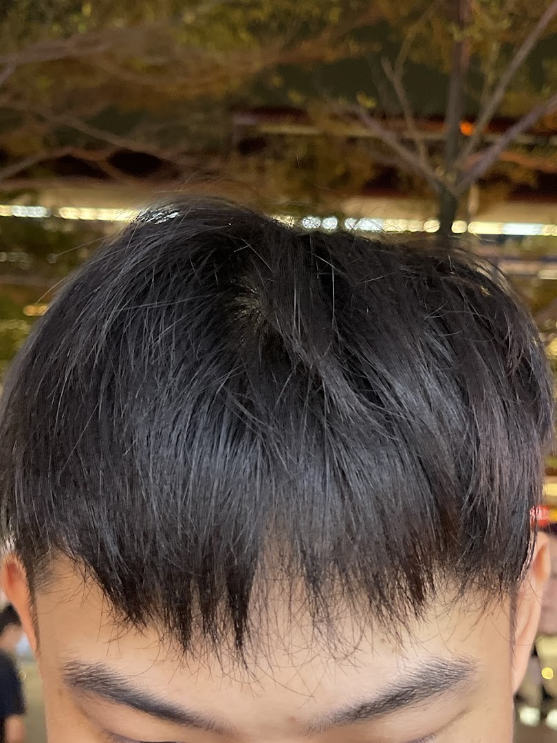 Close-up of a person's dark, styled hair and forehead, likely showcasing a fresh haircut.
