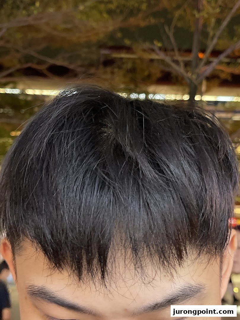 Close-up of a person's dark, styled hair and forehead, likely showcasing a fresh haircut.
