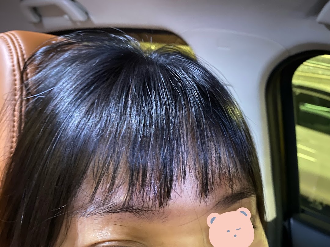 Close-up of a person's dark, shiny hair with bangs, showcasing a fresh salon look.