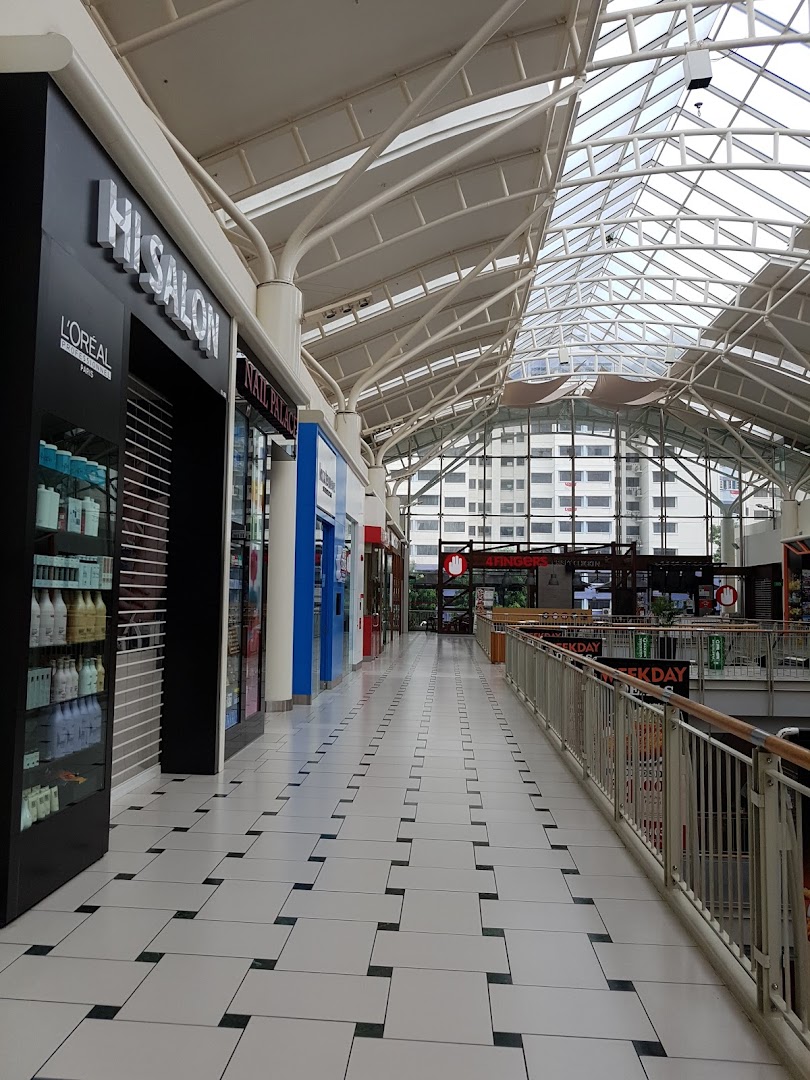 The exterior of HI Salon in a brightly lit mall corridor with a glass ceiling and product display.