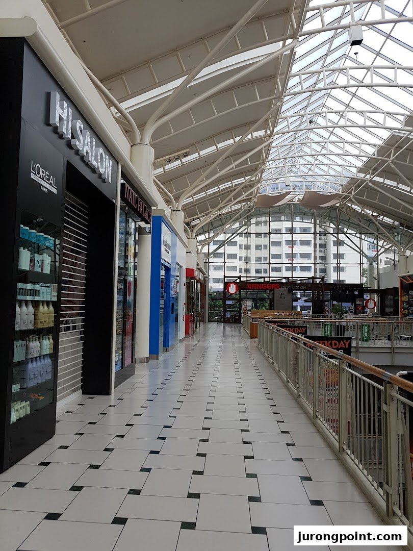 The exterior of HI Salon in a brightly lit mall corridor with a glass ceiling and product display.