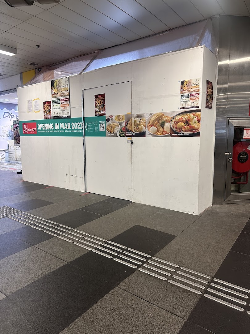 A boarded-up shop front for 'KOO KEE' announcing its opening in March 2023, featuring enticing food images.