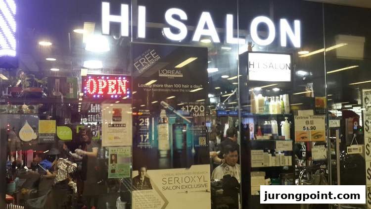 The brightly lit storefront of HI Salon, featuring an 'OPEN' sign and promotional displays for hair and beauty services.