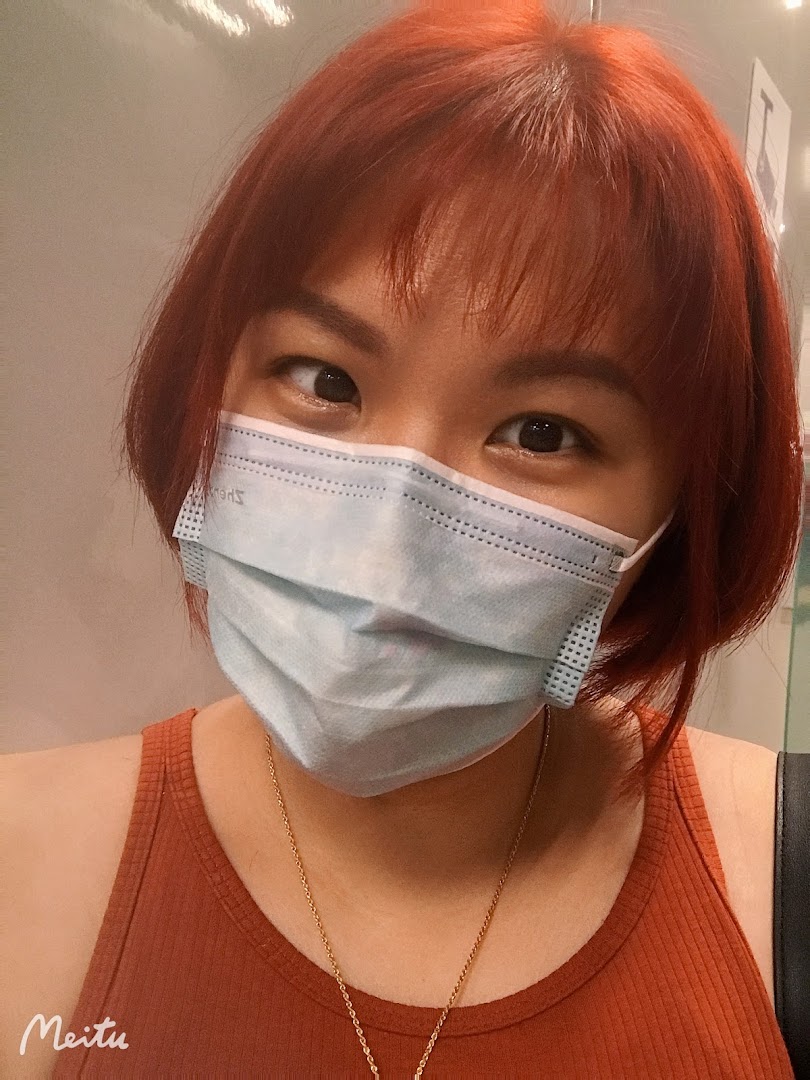 A close-up of a person with vibrant red hair and a face mask.