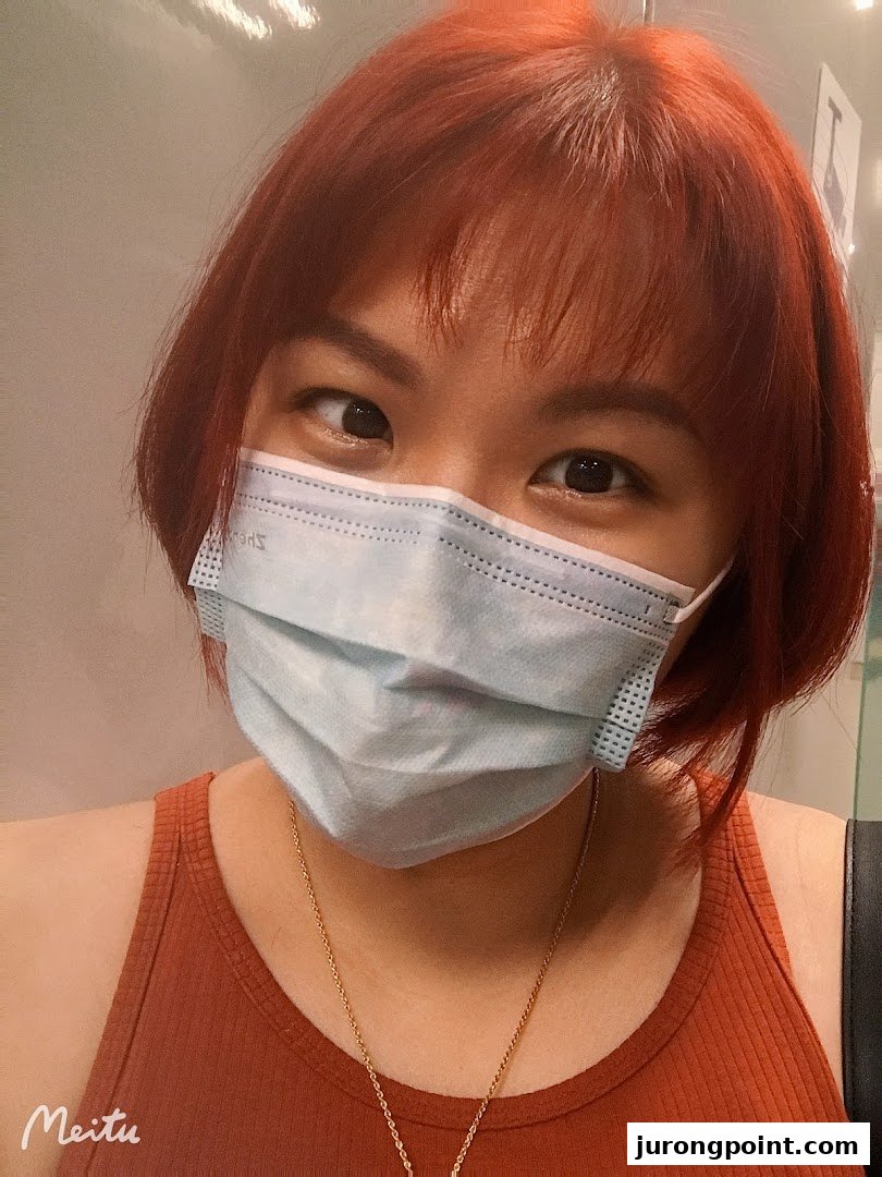 A close-up of a person with vibrant red hair and a face mask.