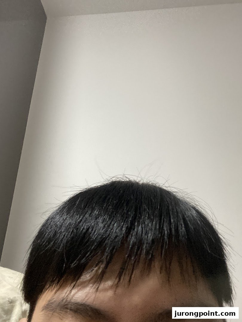 Close-up of a person's black hair and forehead, showcasing hair texture and style.