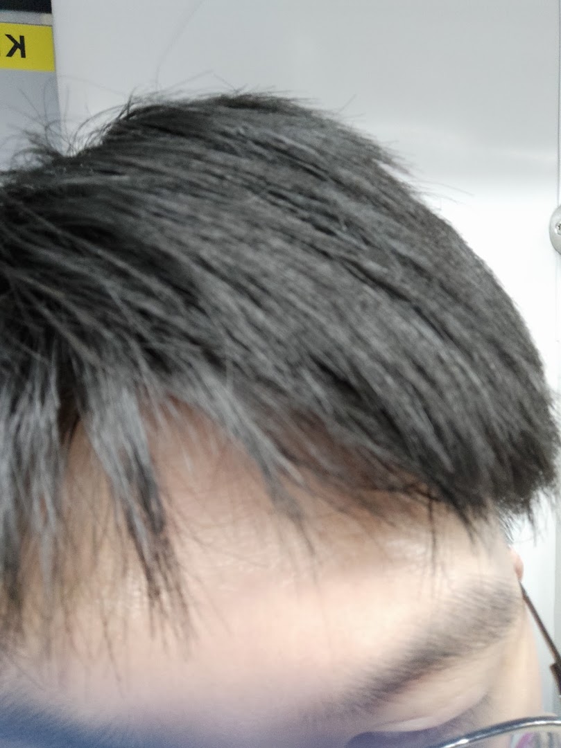 Close-up of a person's dark hair and temple area, possibly showcasing a hair texture or style.
