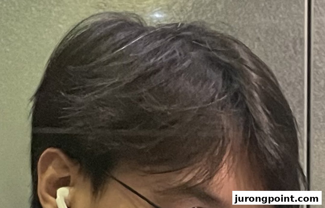 Close-up of a person's head, featuring dark hair and an earbud.